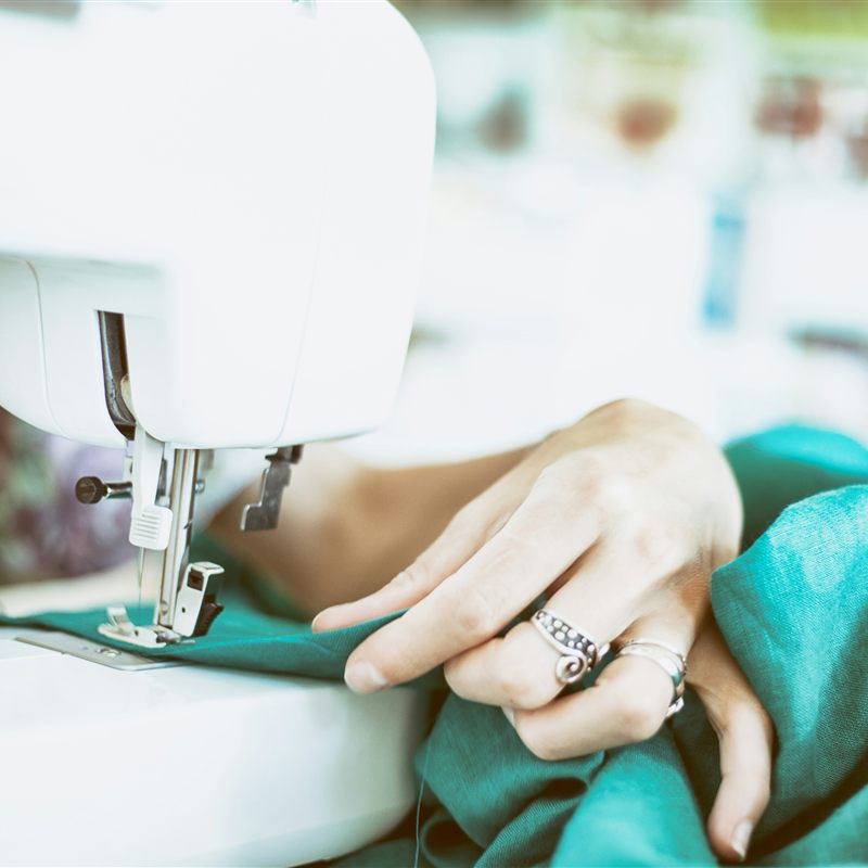 Mains guidant un tissu sous l'aiguille d'une machine à coudre
